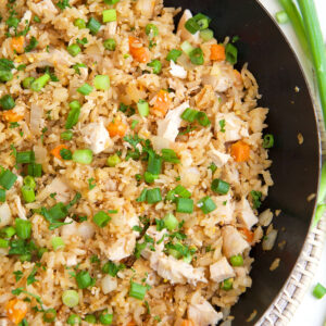 Half of a skillet is shown in the photo. It is filled with chicken fried rice.