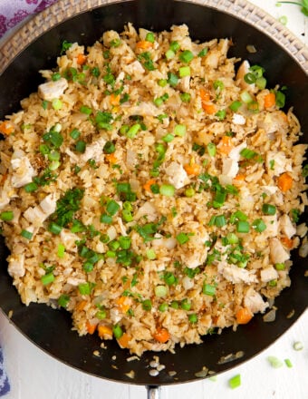 A skillet is filled with cooked chicken fried rice.