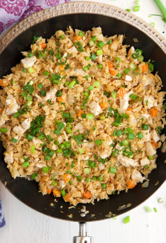 A skillet is filled with cooked chicken fried rice.