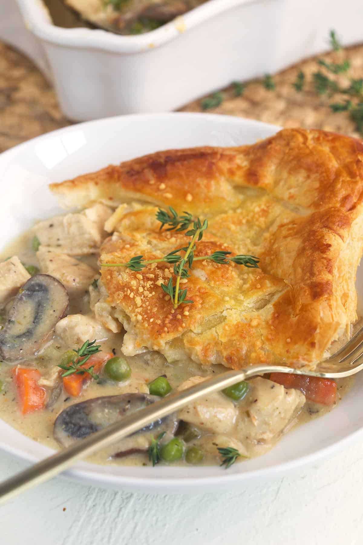 A spoon is placed next to a single portion of chicken pot pie. 
