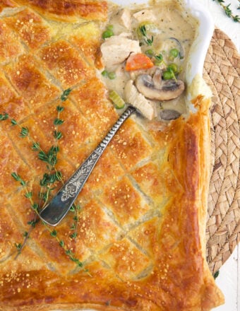 A serving spoon is placed in a baking dish filled with chicken pot pie casserole.