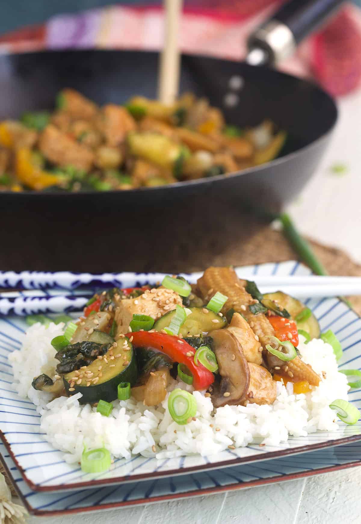 Chicken stir fry is served on top of a pile of white rice. 