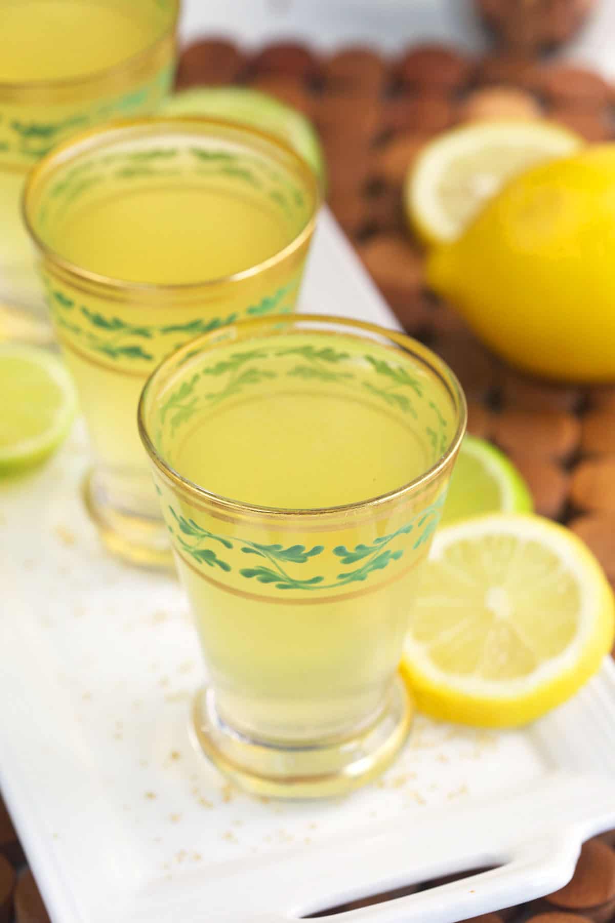 Lemon slices are placed all around several green tea shots. 