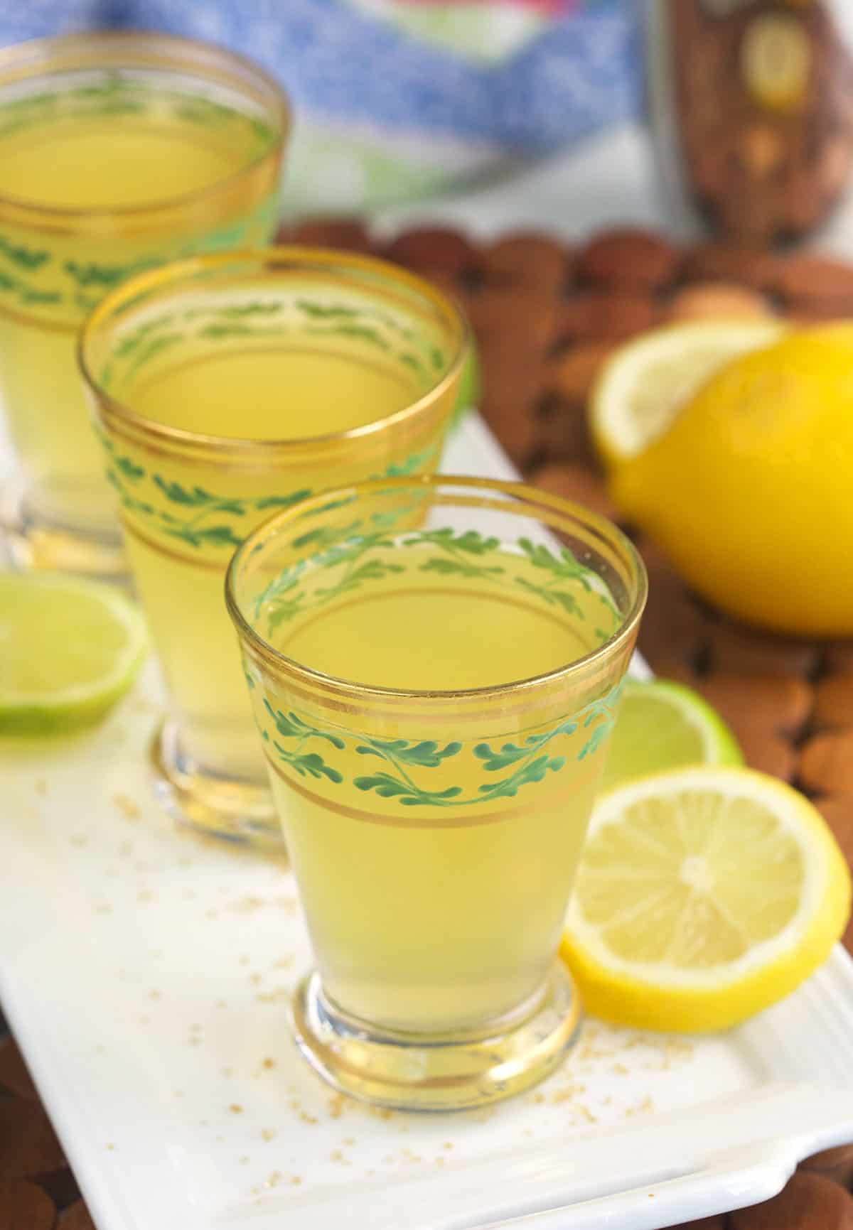 Three green tea shots are lined up on a white plate. 