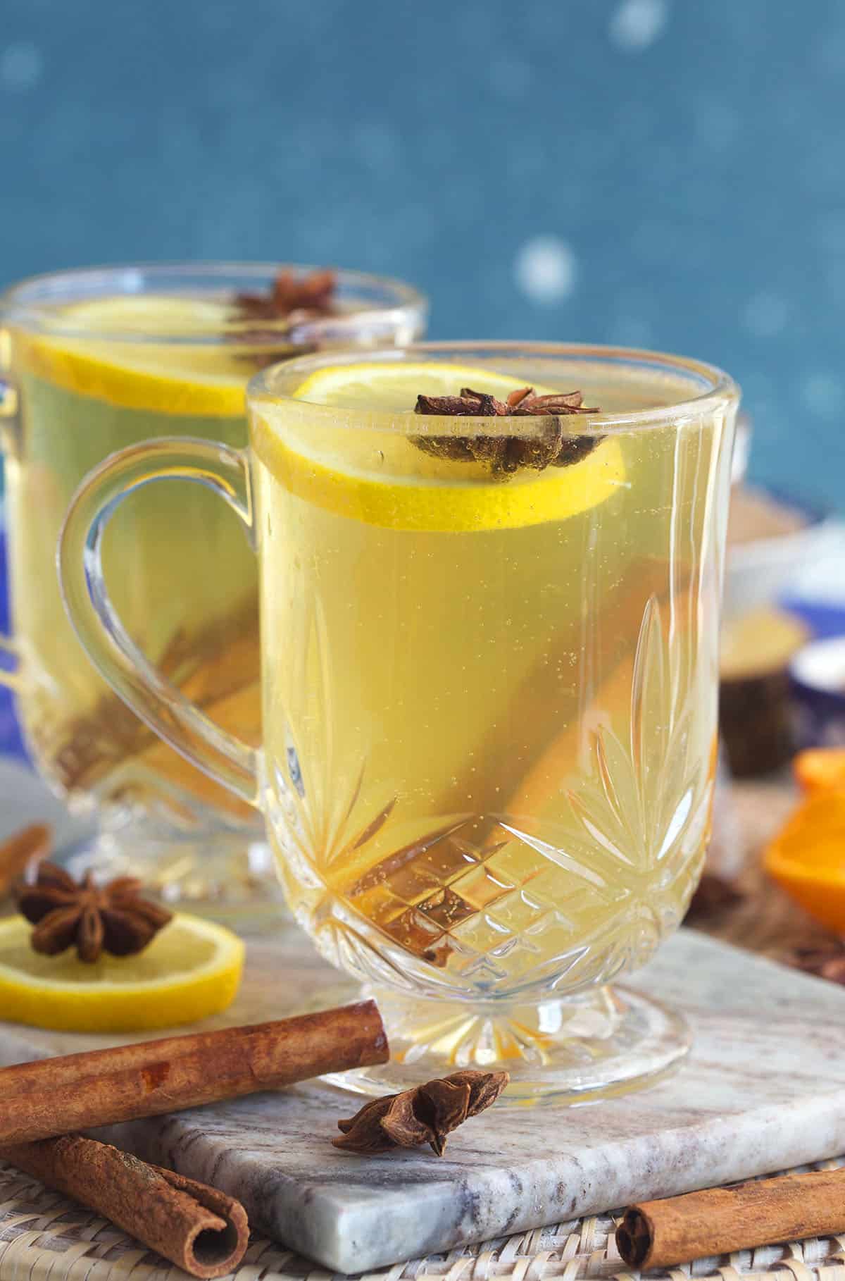 Lemon slices, star anise and cinnamon sticks are placed in a mug of hot toddy. 