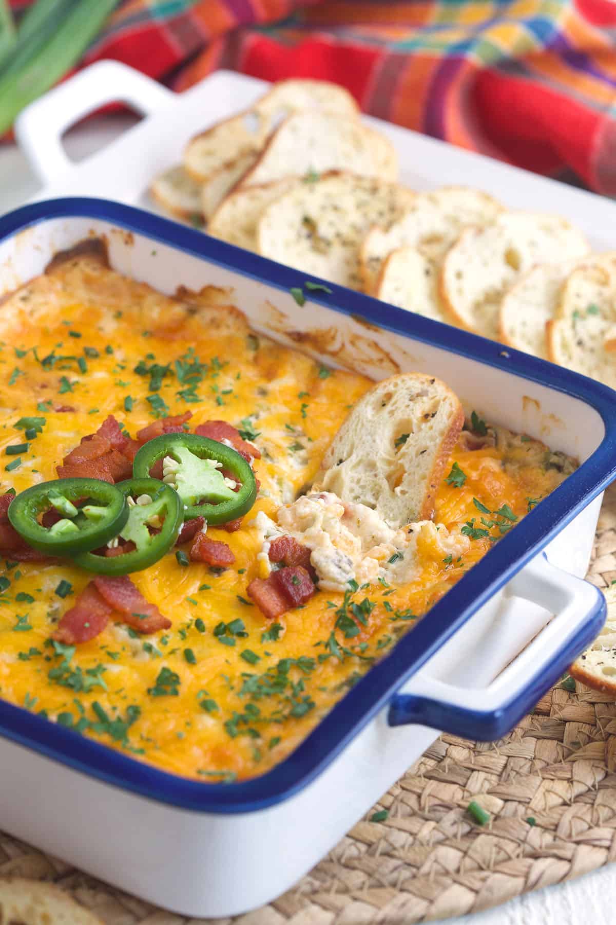 Jalapenos, bacon, chives and green onions top a baking dish filled with dip. 