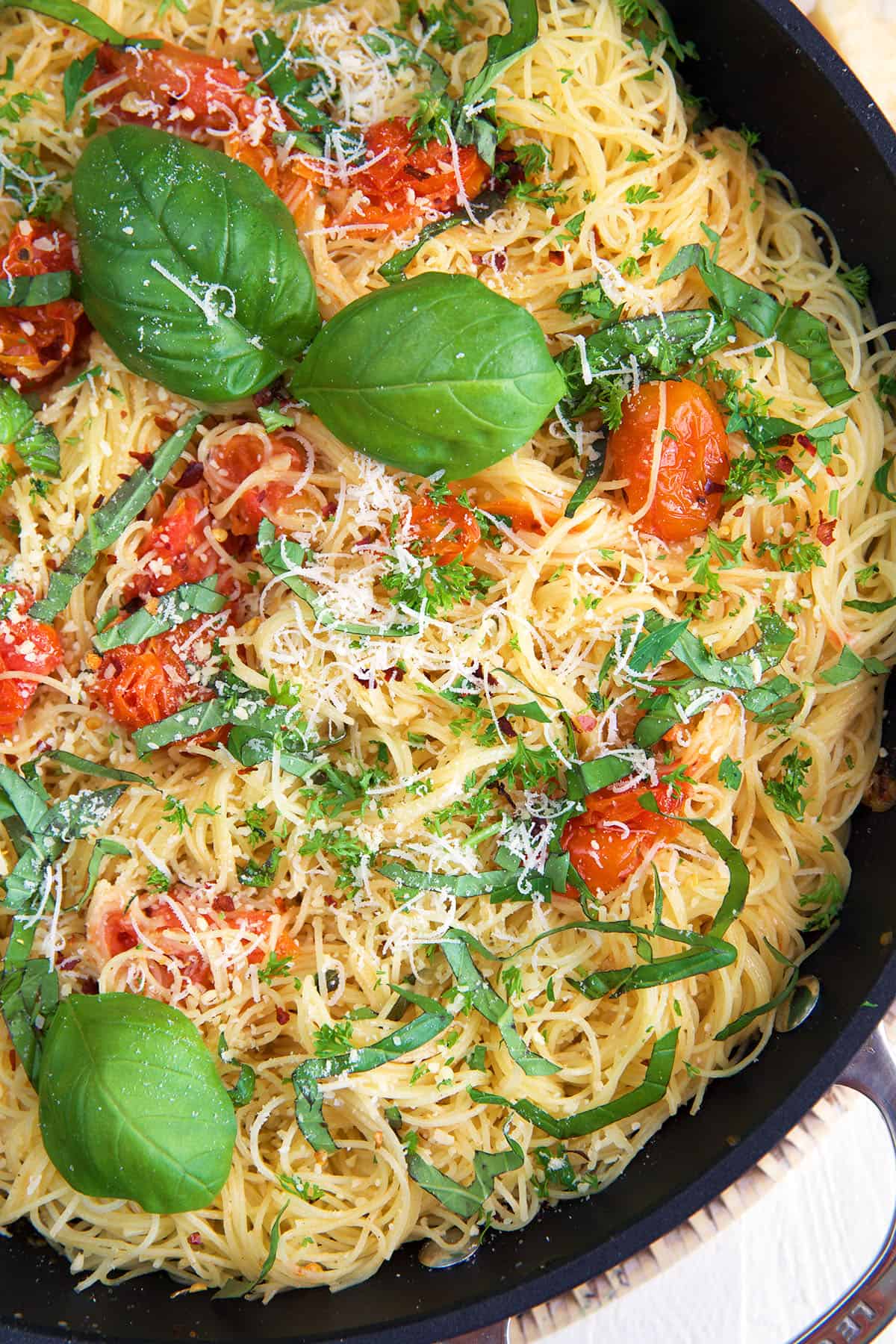 Basil garnishes a skillet filled with cooked pasta. 