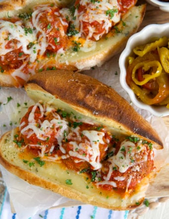 Two subs are placed next to a small bowl of peppers.