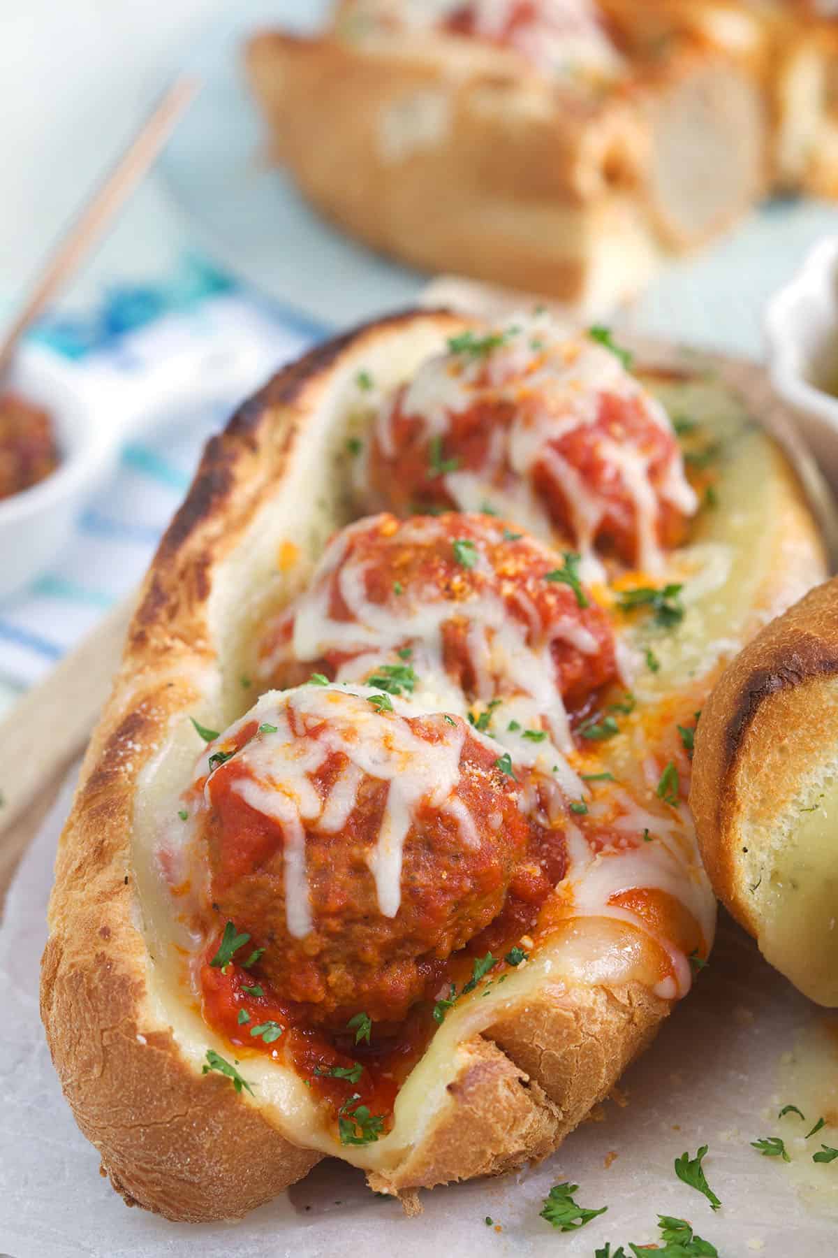 A meatball sub is garnished with fresh parsley. 