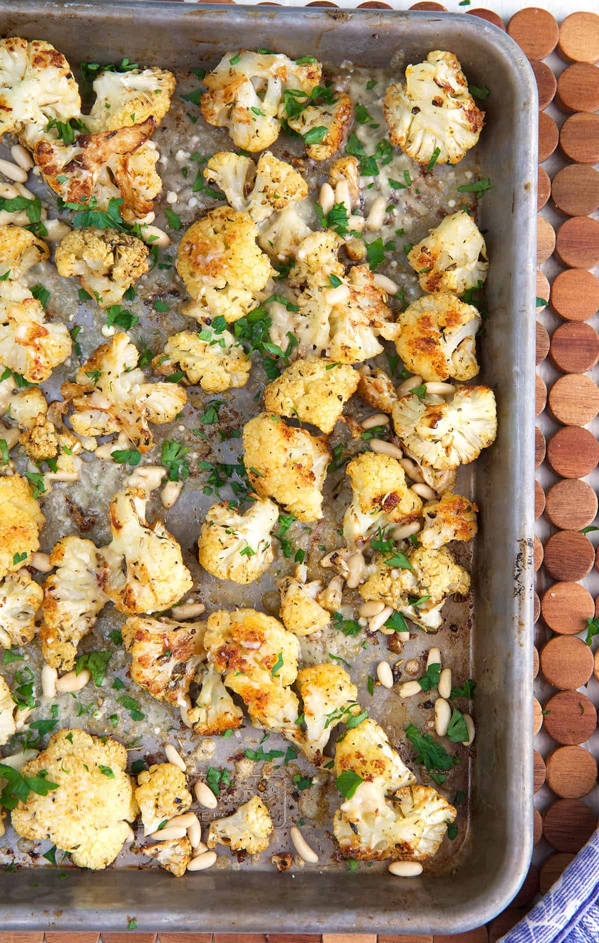 Roasted cauliflower is spread all over a baking sheet. 