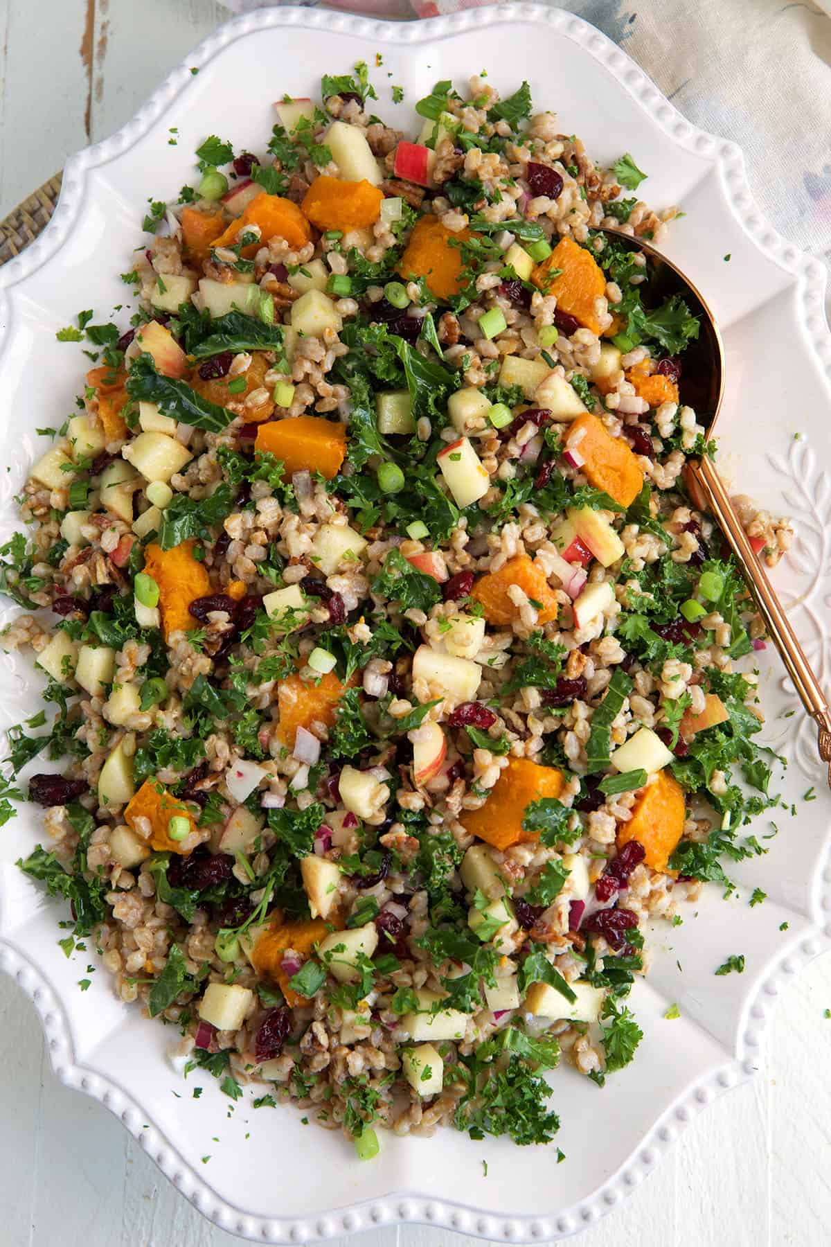 A white serving dish is topped with farro salad. 