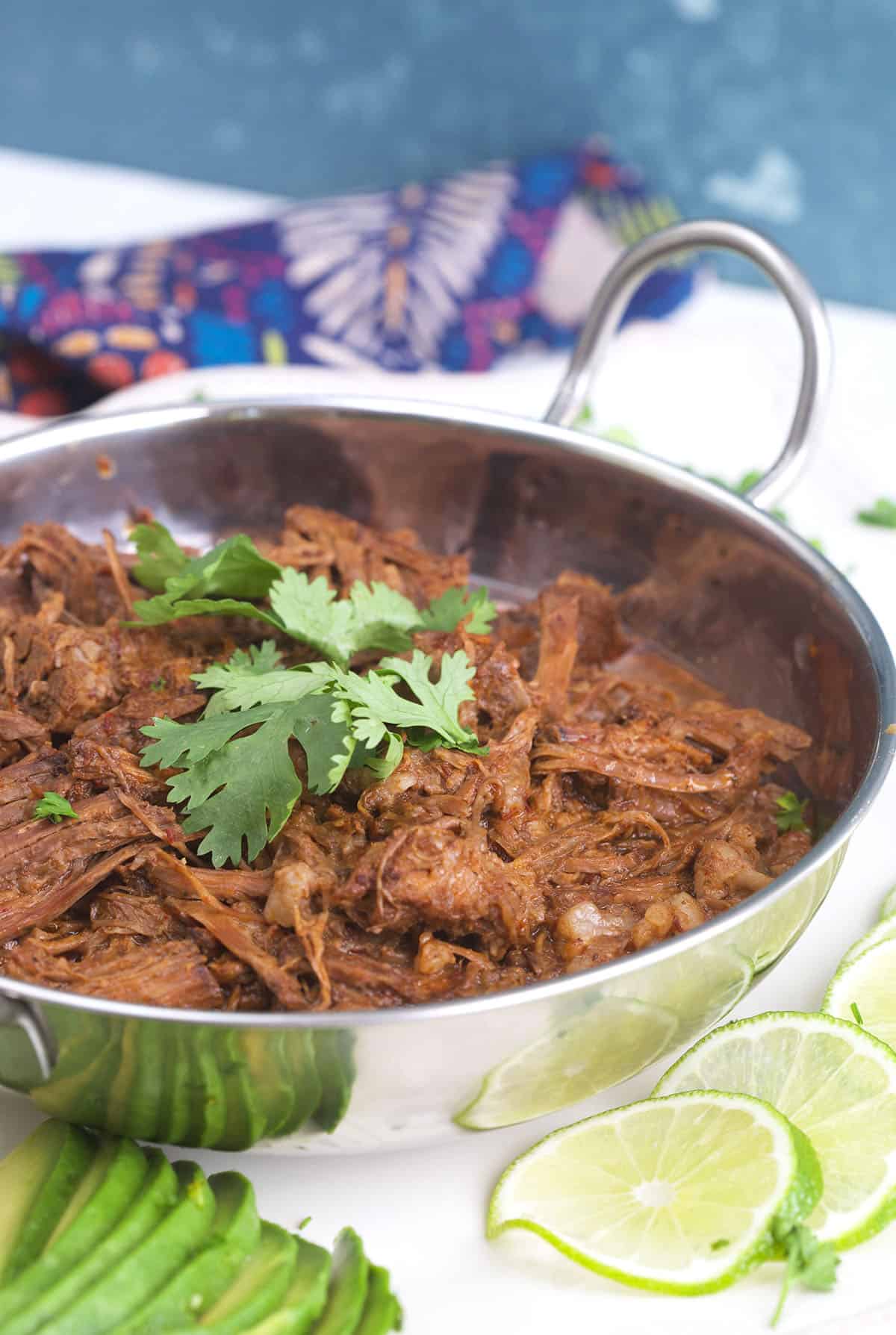 Fresh cilantro garnished a silver bowl filled with beef barbacoa. 