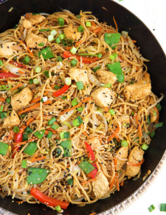 A large black skillet is filled with cooked chicken lo mein.