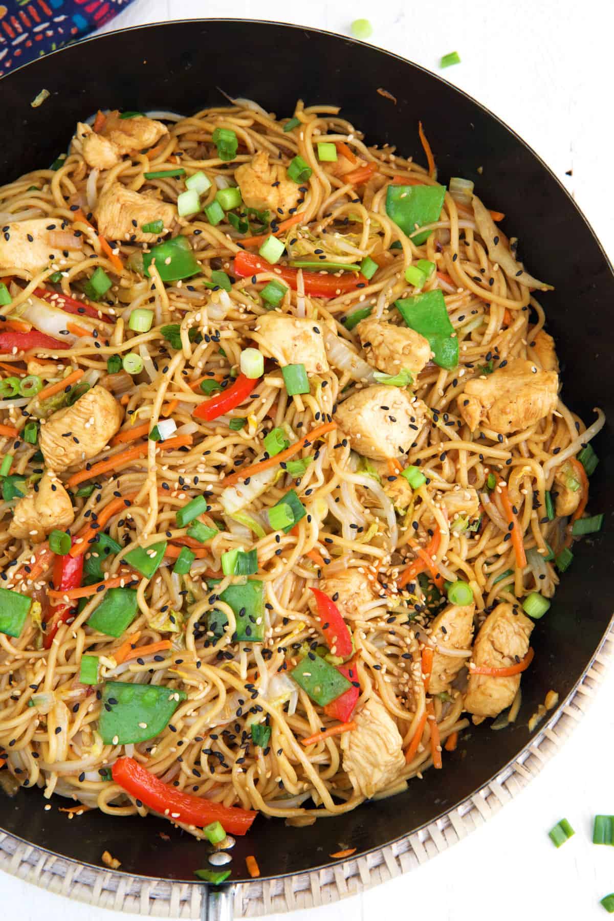 A large black skillet is filled with cooked chicken lo mein.