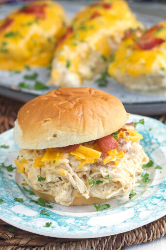 A bacon ranch chicken sandwich is placed in front of several cooked chicken breasts.