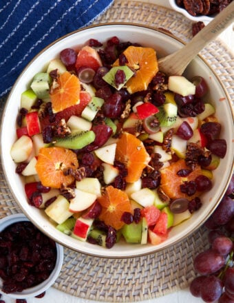 A white bowl is filled with fruit salad.