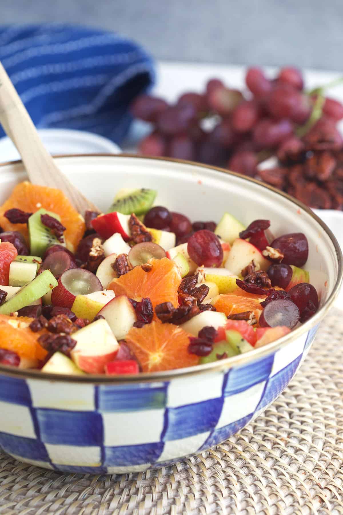 Fruit salad is in a blue and white checkered bowl. 
