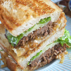 A halved meatloaf sandwich is stacked on a plate.