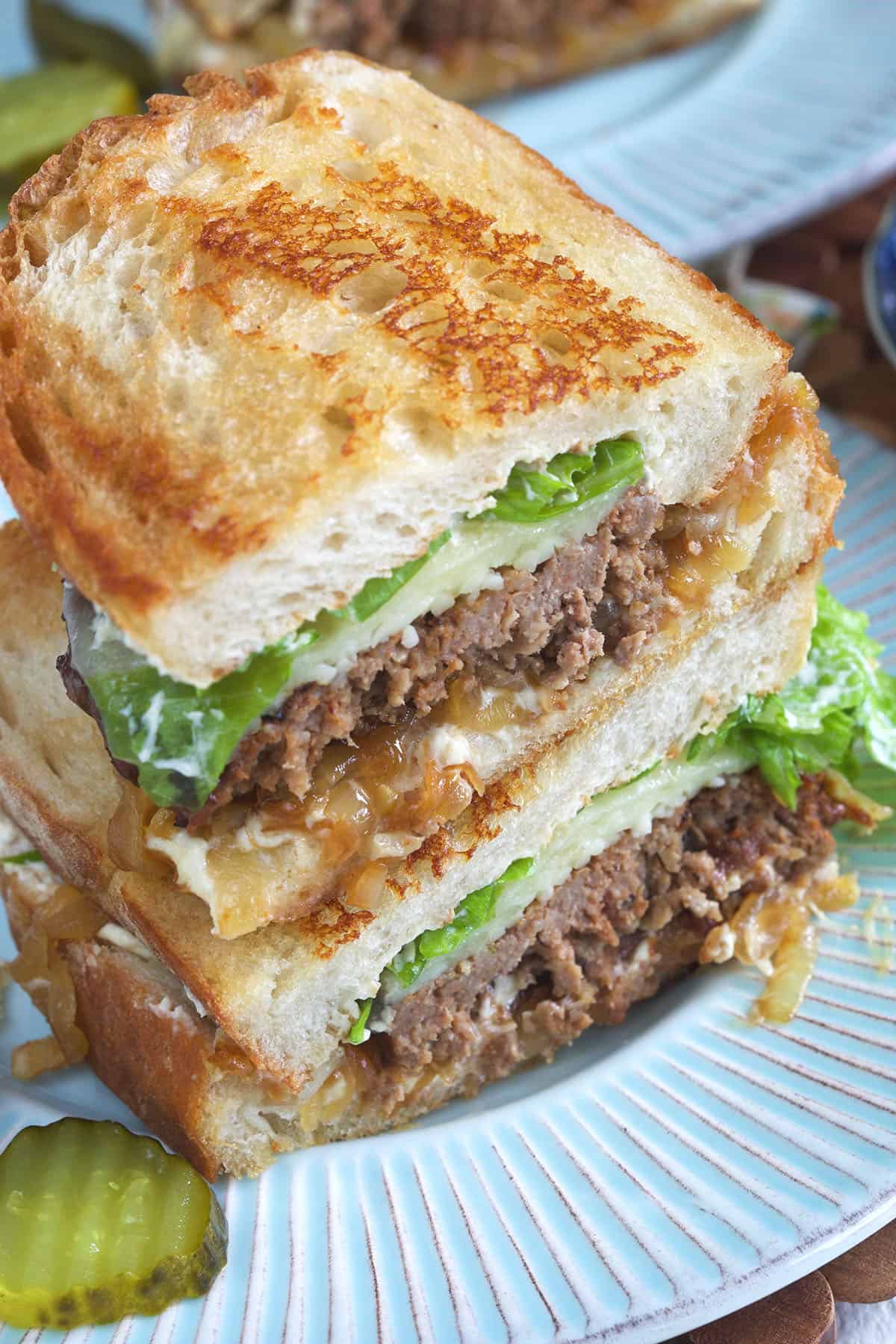 A halved meatloaf sandwich is stacked on a plate.