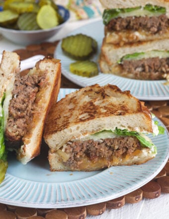 A halved meatloaf sandwich is placed on a round plate.