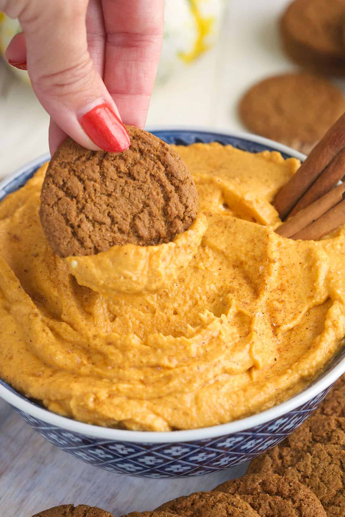 A cookie is being dipped into pumpkin dip. 