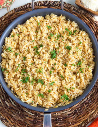 A large skillet is filled with cooked rice pilaf.