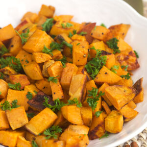 Herbs garnish a serving of roasted sweet potatoes.