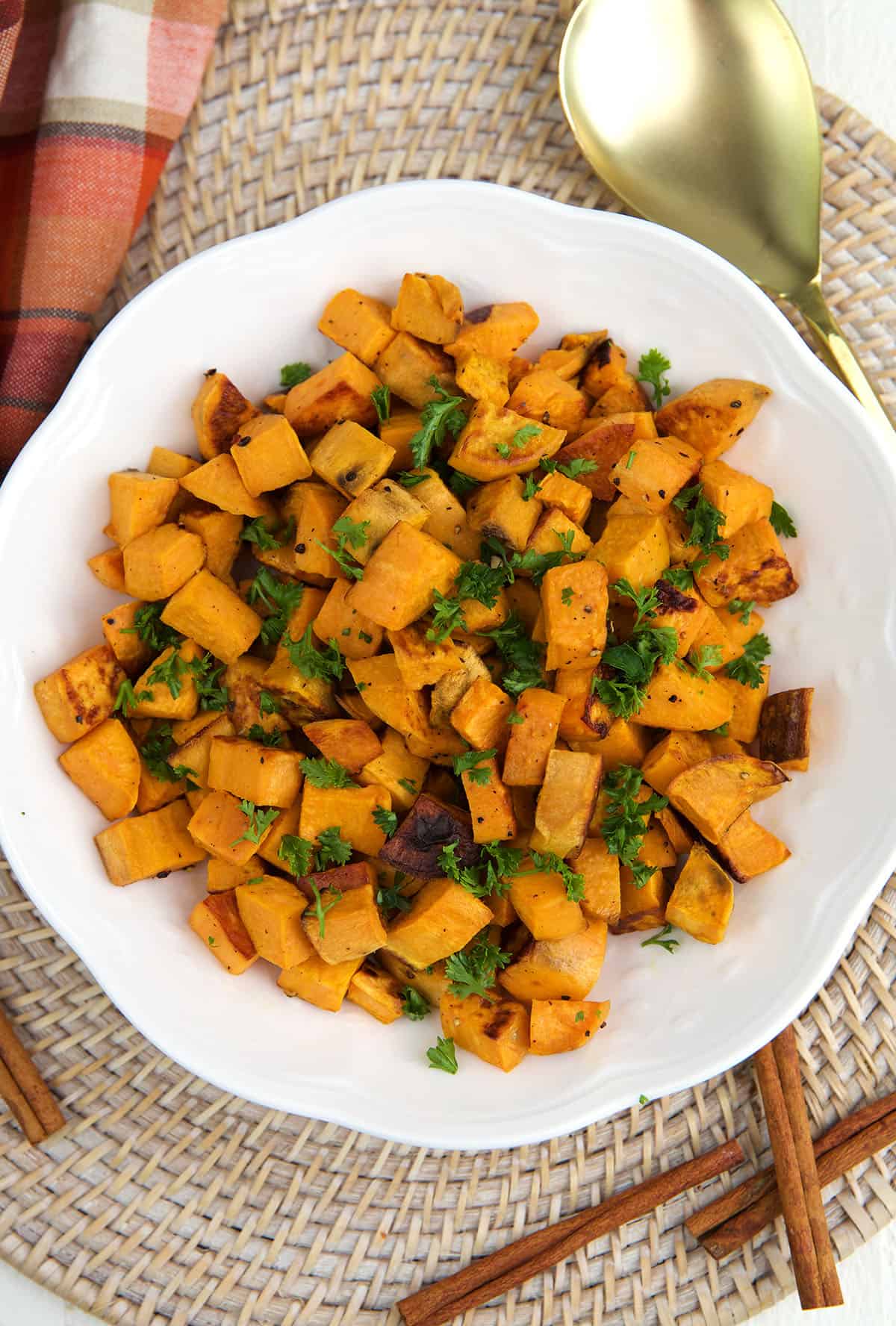 Roasted sweet potatoes are placed on a round white plate.