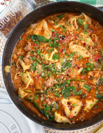 A black pot is filled with sausage tortellini soup.