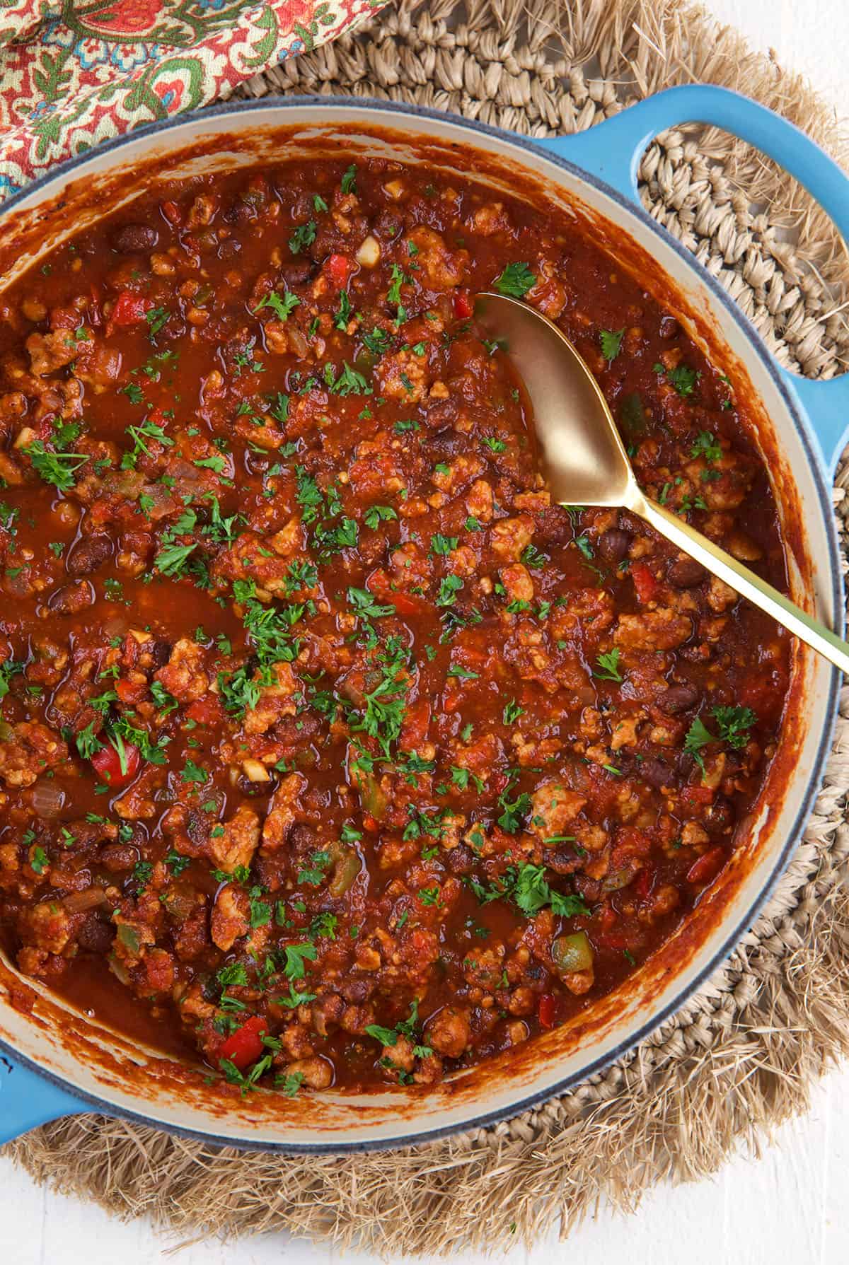 A big serving spoon is placed in a pot of chili. 