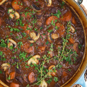 A dutch oven is filled with cooked beef bourguignon.