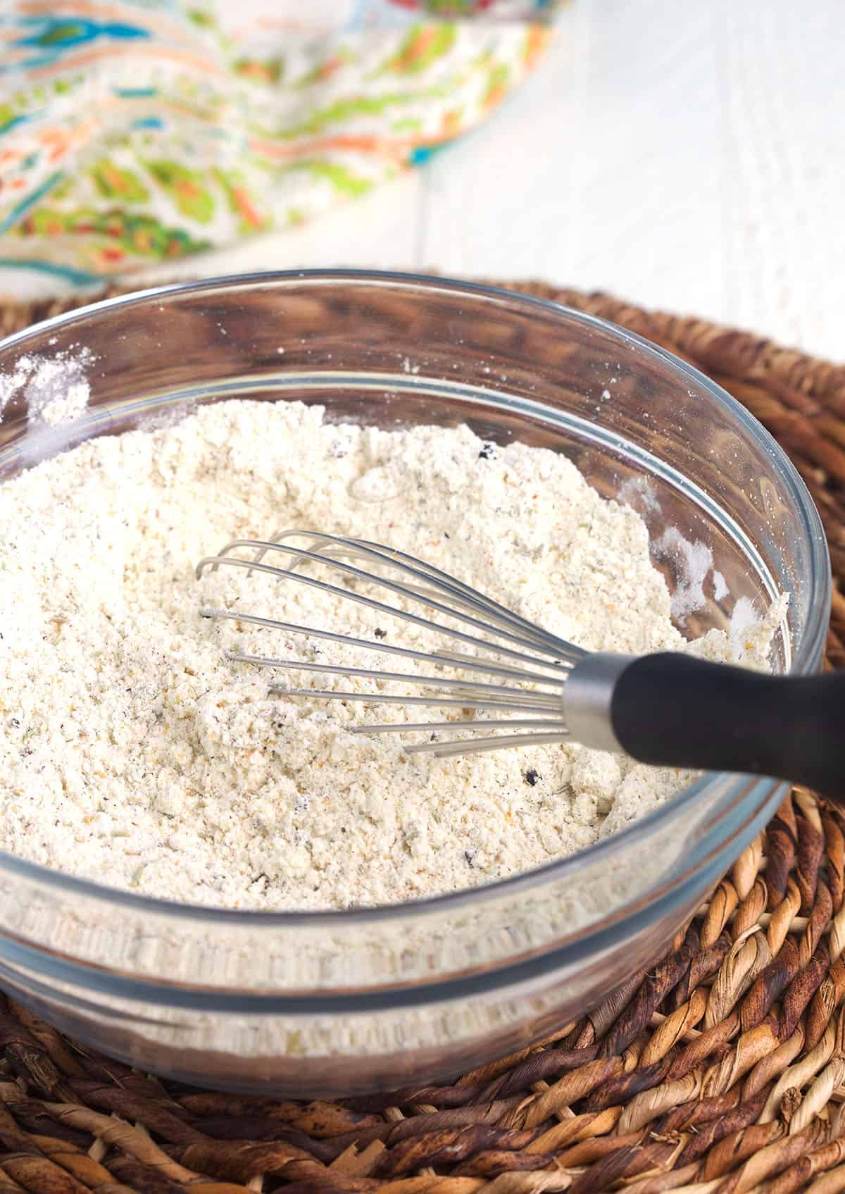 A whisk is stirring ingredients together in a mixing bowl.