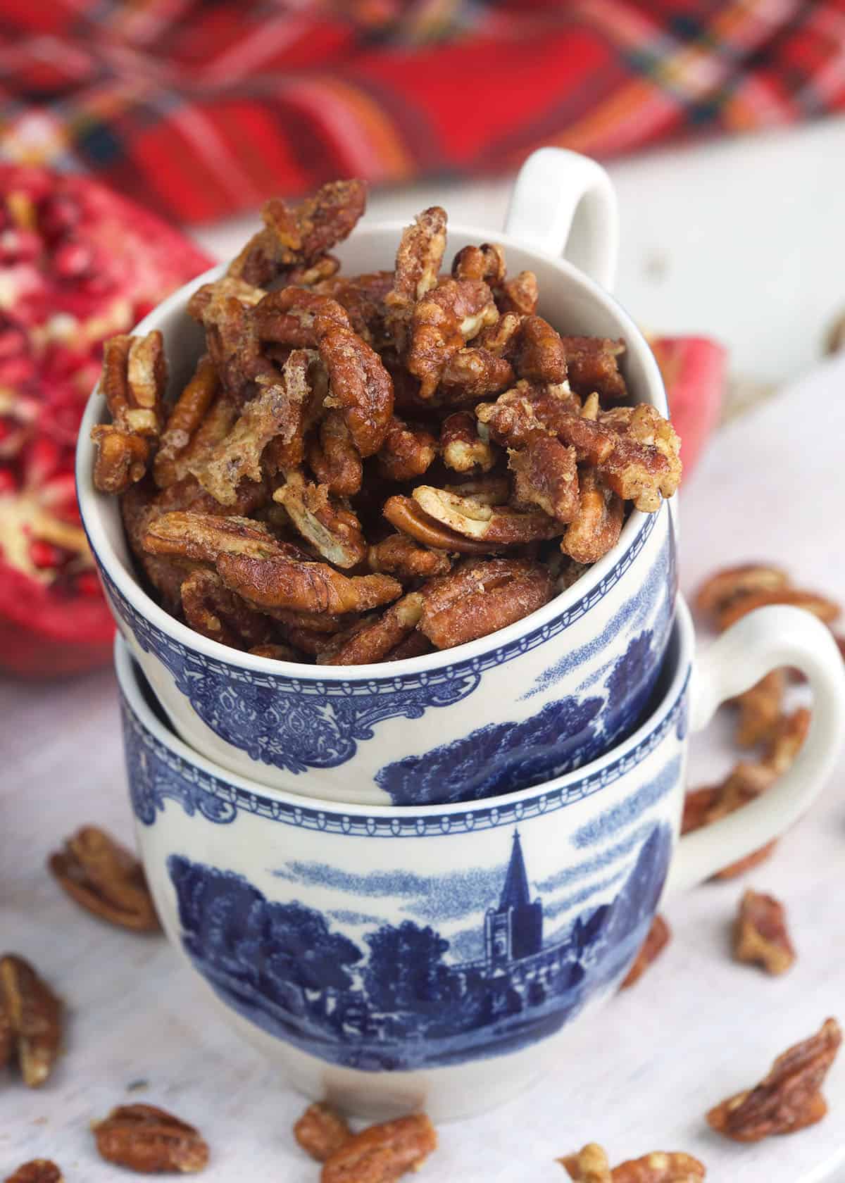 Stacked teacups are filled with candied pecans. 