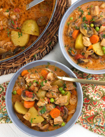 Two bowls of chicken stew are placed next to a pot.