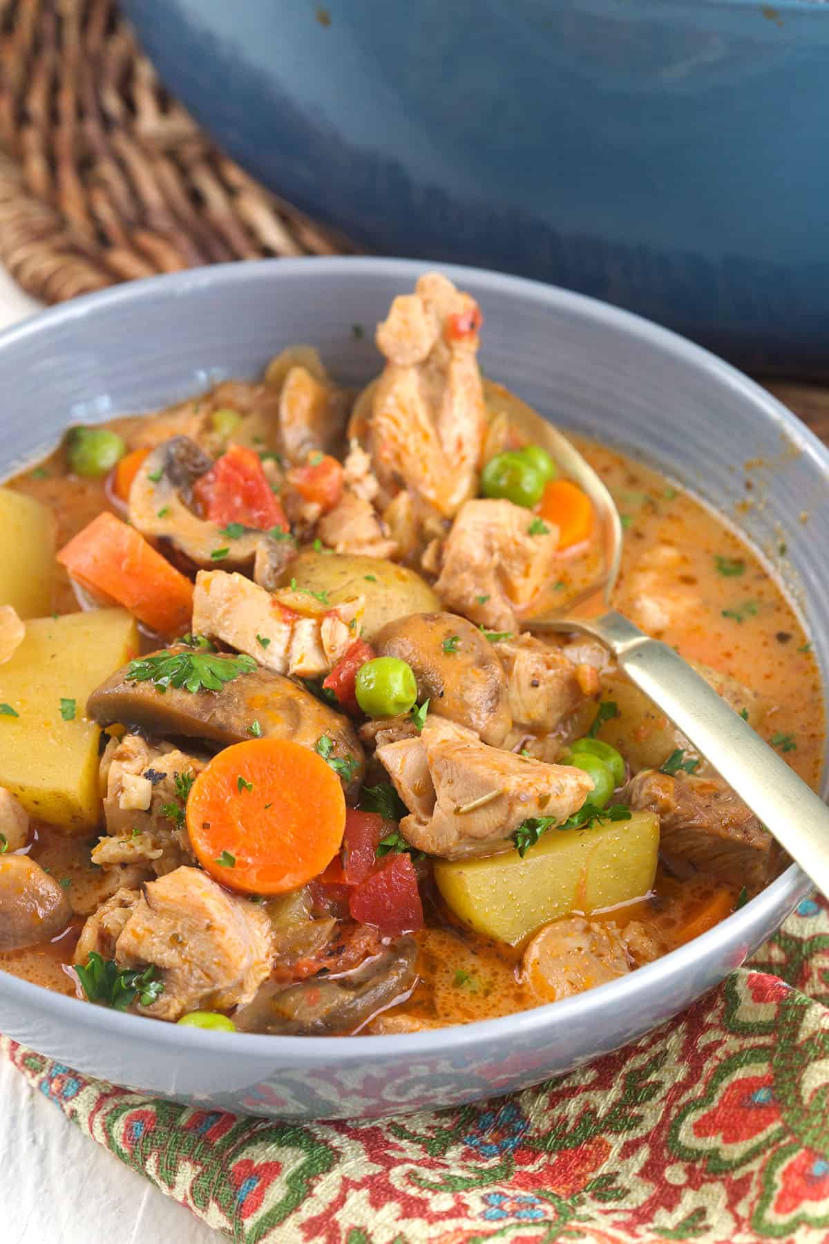 A spoon is placed in a bowl filled with chicken stew. 