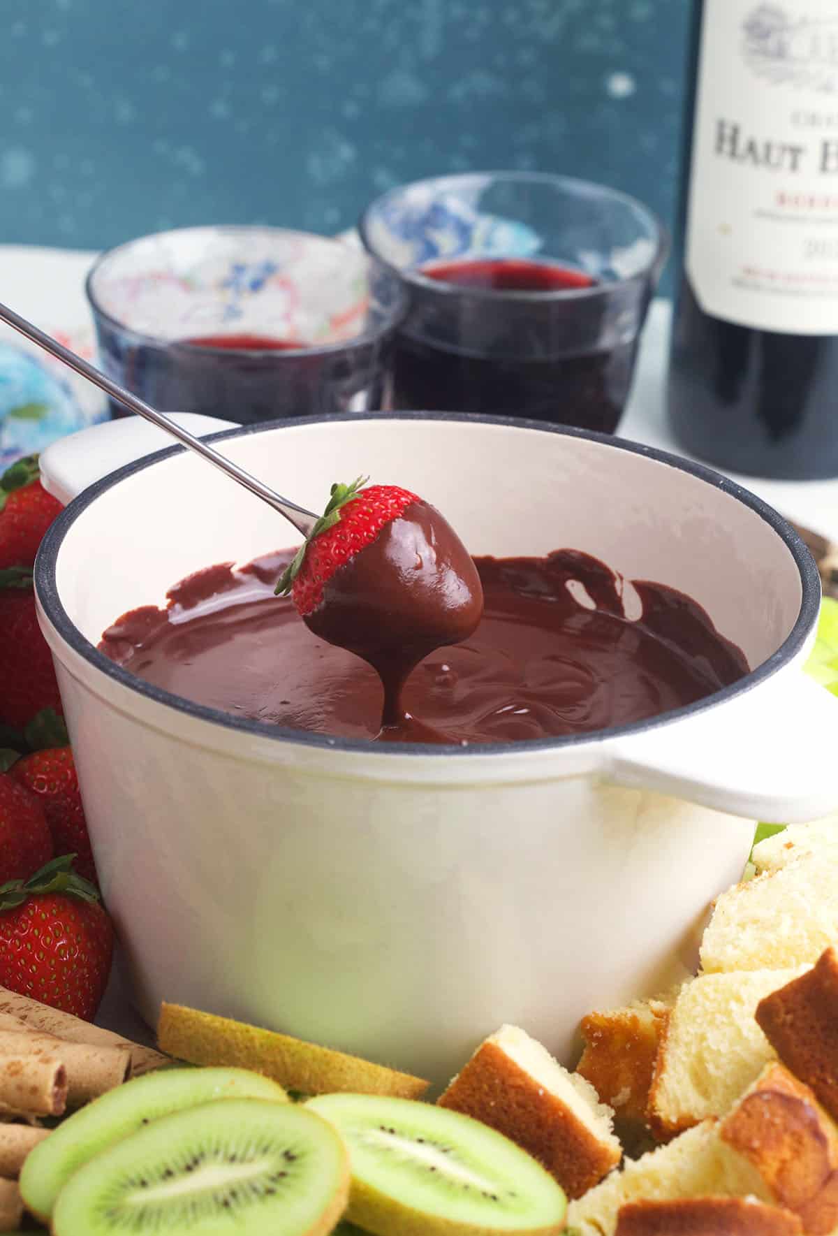 A strawberry is being dipped in chocolate fondue.