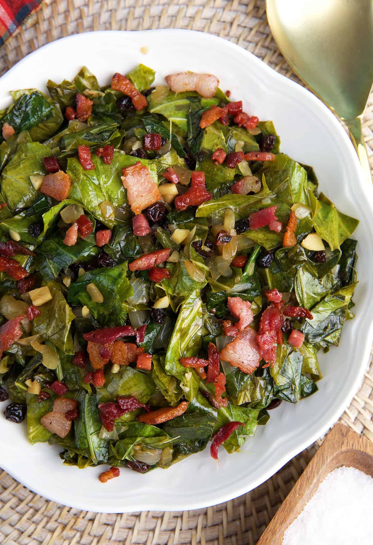 A large white bowl is filled with cooked collard greens. 