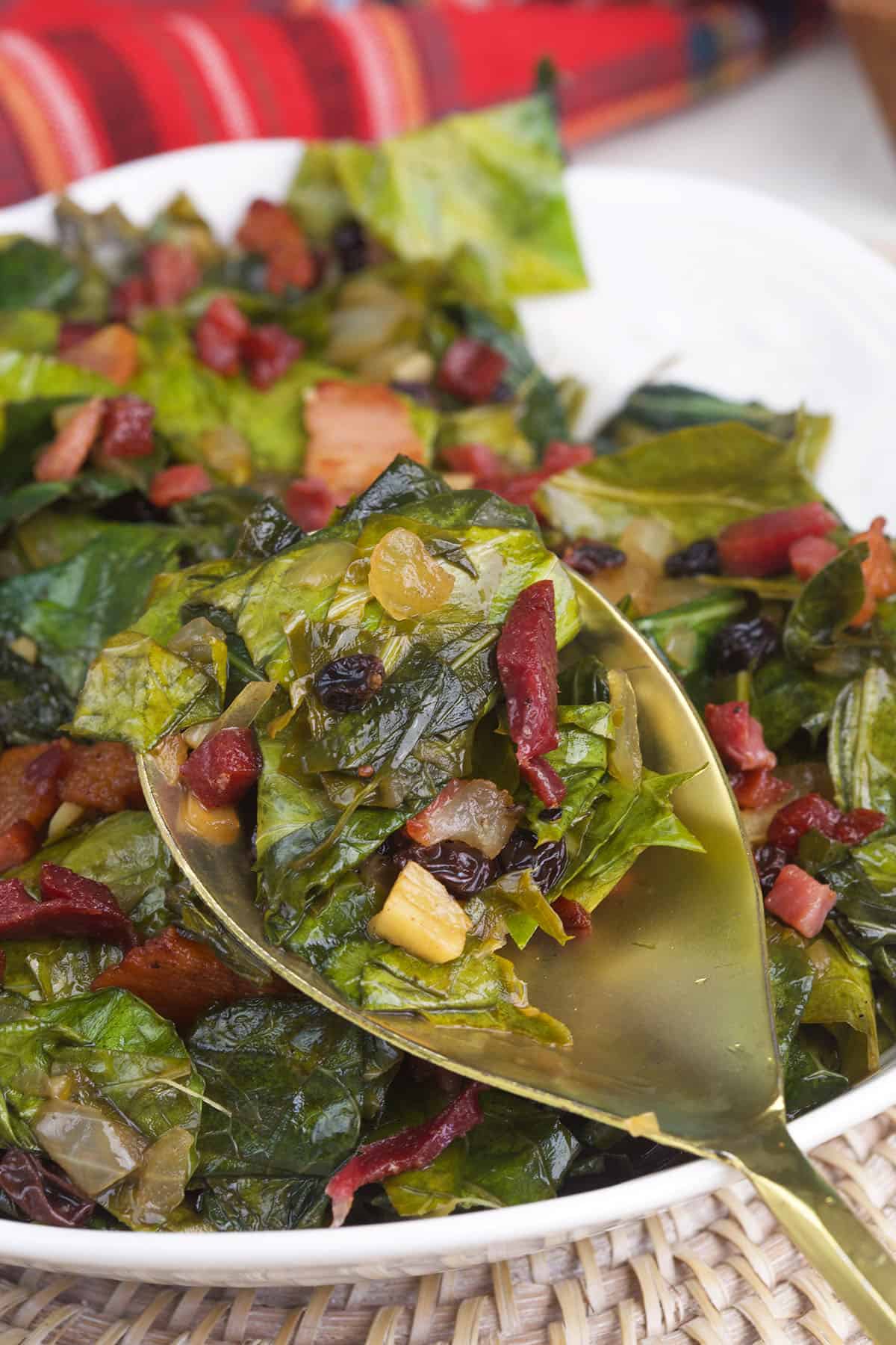 A scoop of collard greens is being held above the rest of the dish.