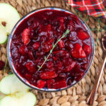 Halved apples are placed next to a bowl of chutney.