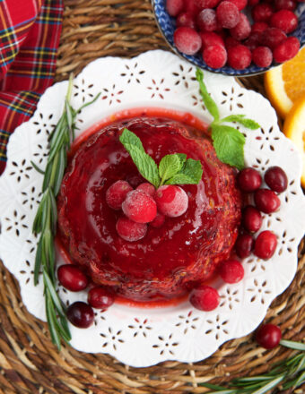 A cranberry jello salad is garnished with herbs and berries.