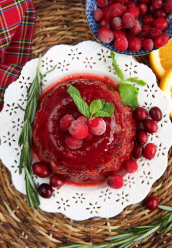A cranberry jello salad is garnished with herbs and berries.