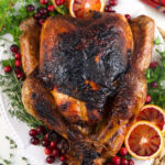 A whole roasted turkey is garnished and presented on a serving plate.