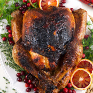 A whole roasted turkey is garnished and presented on a serving plate.