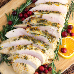 A sliced turkey breast is presented with rosemary and cranberries.