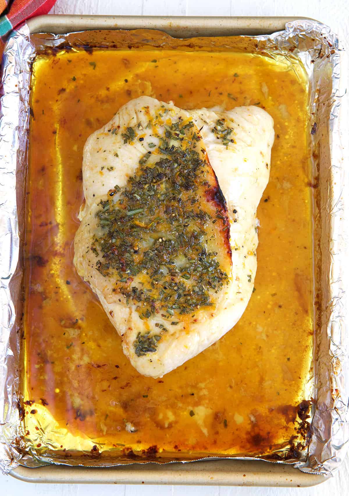 A roasted turkey breast is placed on a baking sheet. 