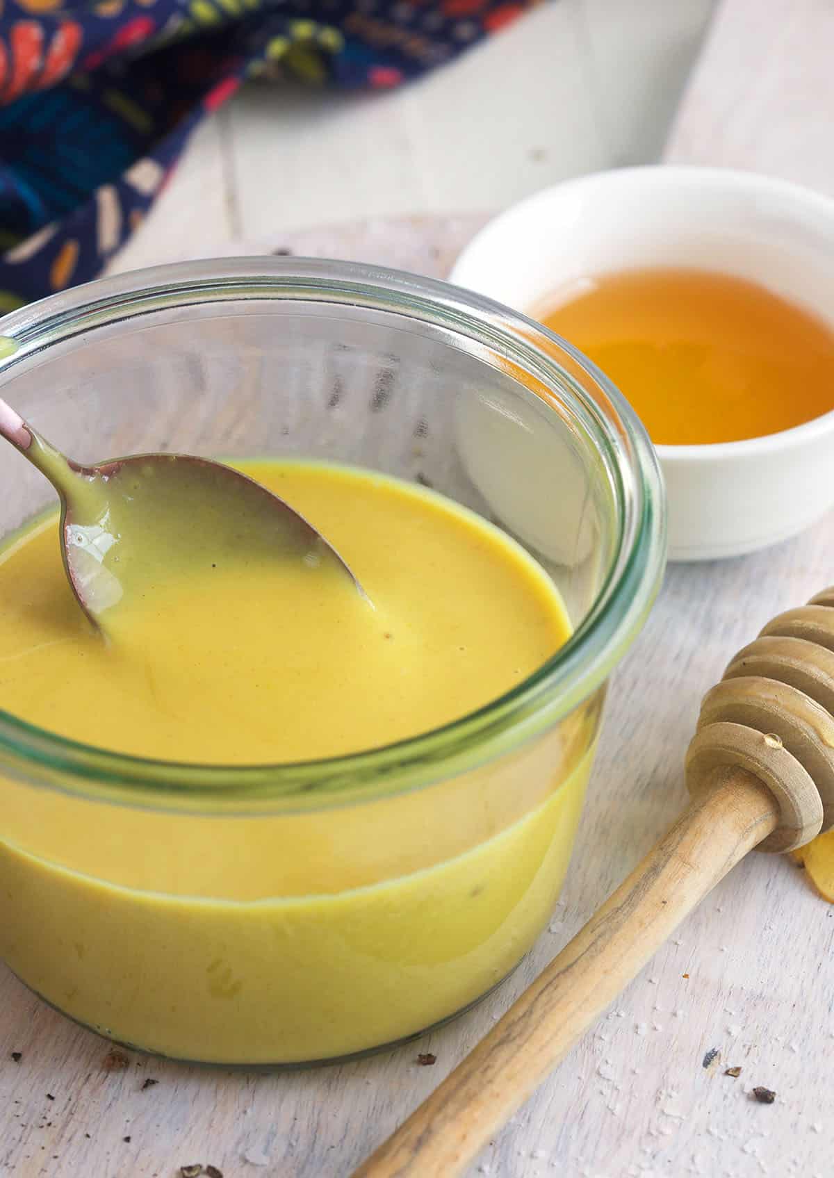 A spoon is placed in a bowl of honey mustard. 