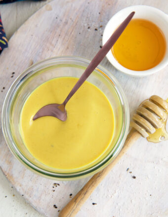 A small bowl full of honey mustard is placed next to a small bowl of honey.
