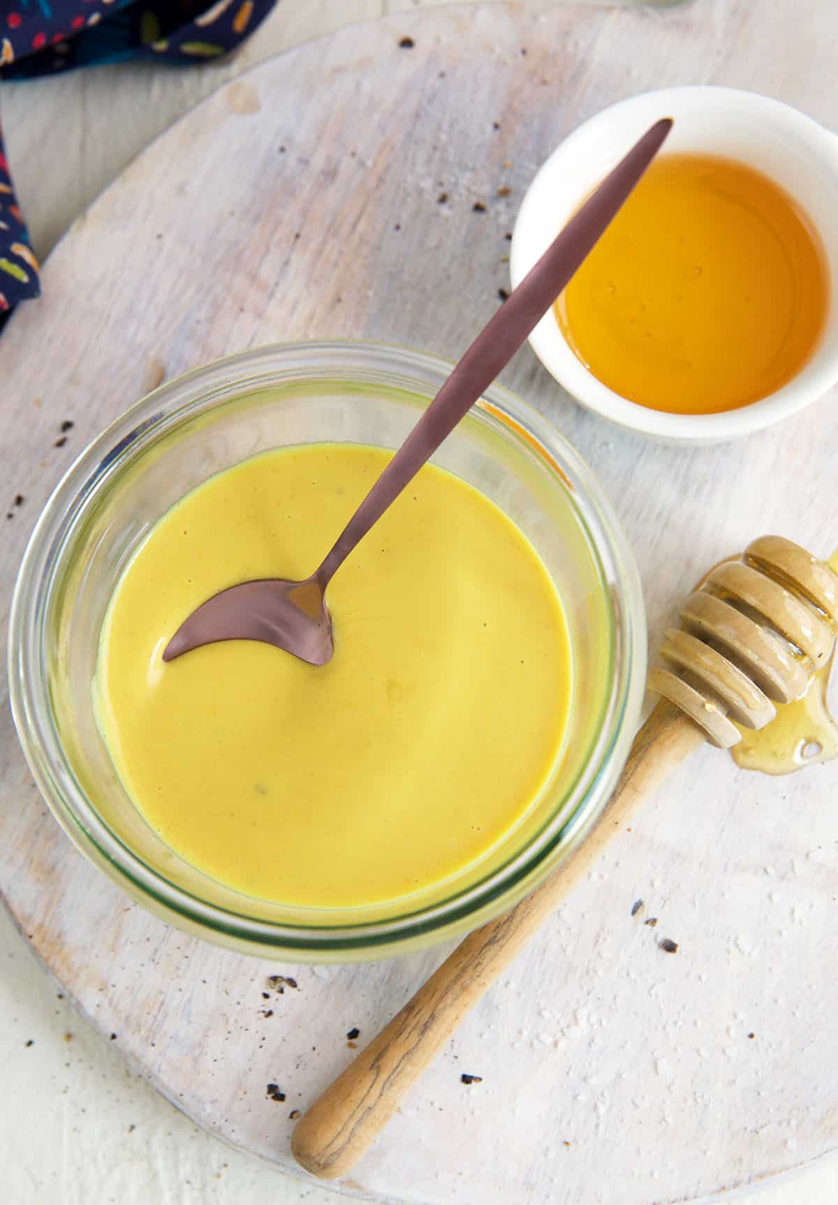 A small bowl full of honey mustard is placed next to a small bowl of honey.