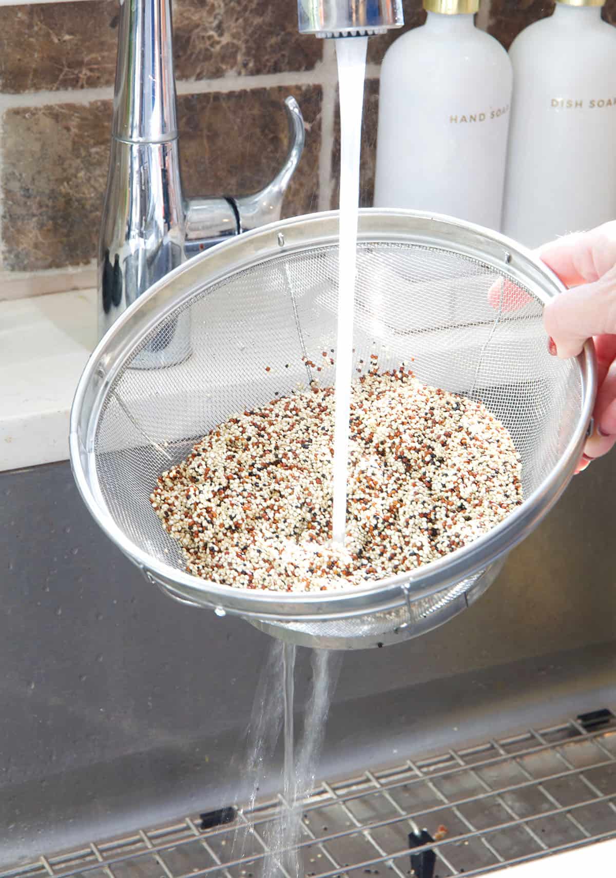 Water is rinsing quinoa through a sieve. 