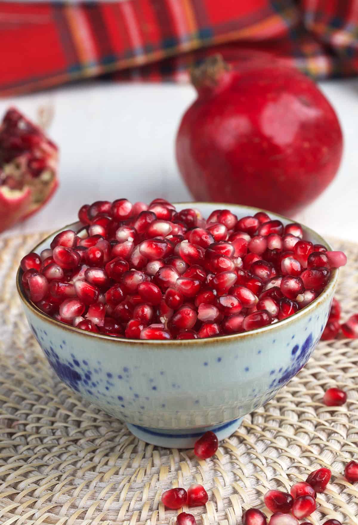 A white and blue bowl is filled to the brim with pomegranate seeds. 